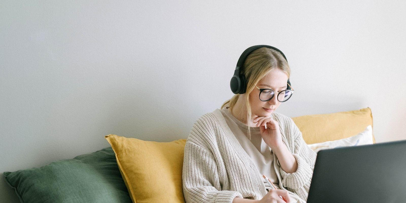 Photo of woman with headphones looking at her laptop
